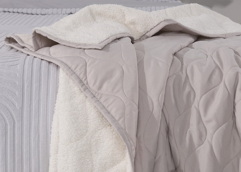 A sherpa blanket on the edge of a bed.