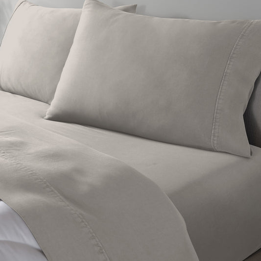 Light beige bed sheet set with matching pillowcases on a bed, shown in a close-up view.