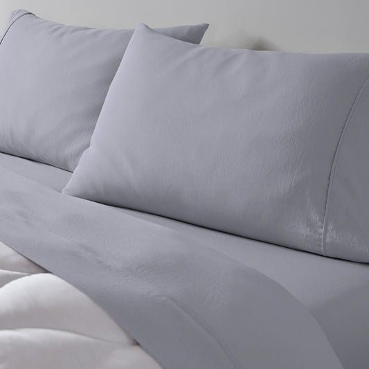 A light grey essential sheet set on a made bed.