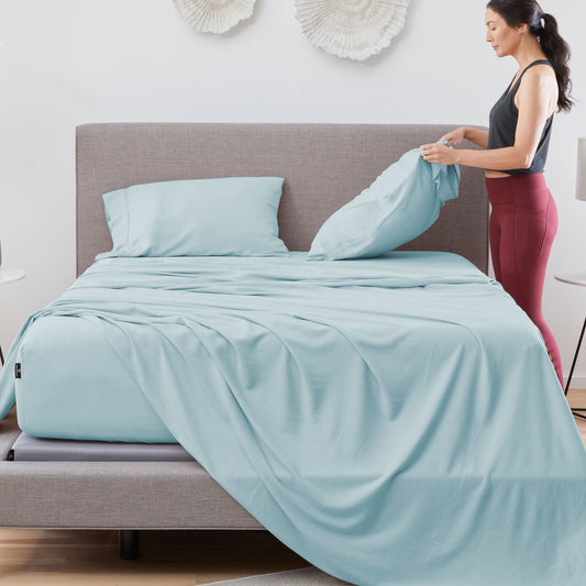 A woman making a California King bed. 