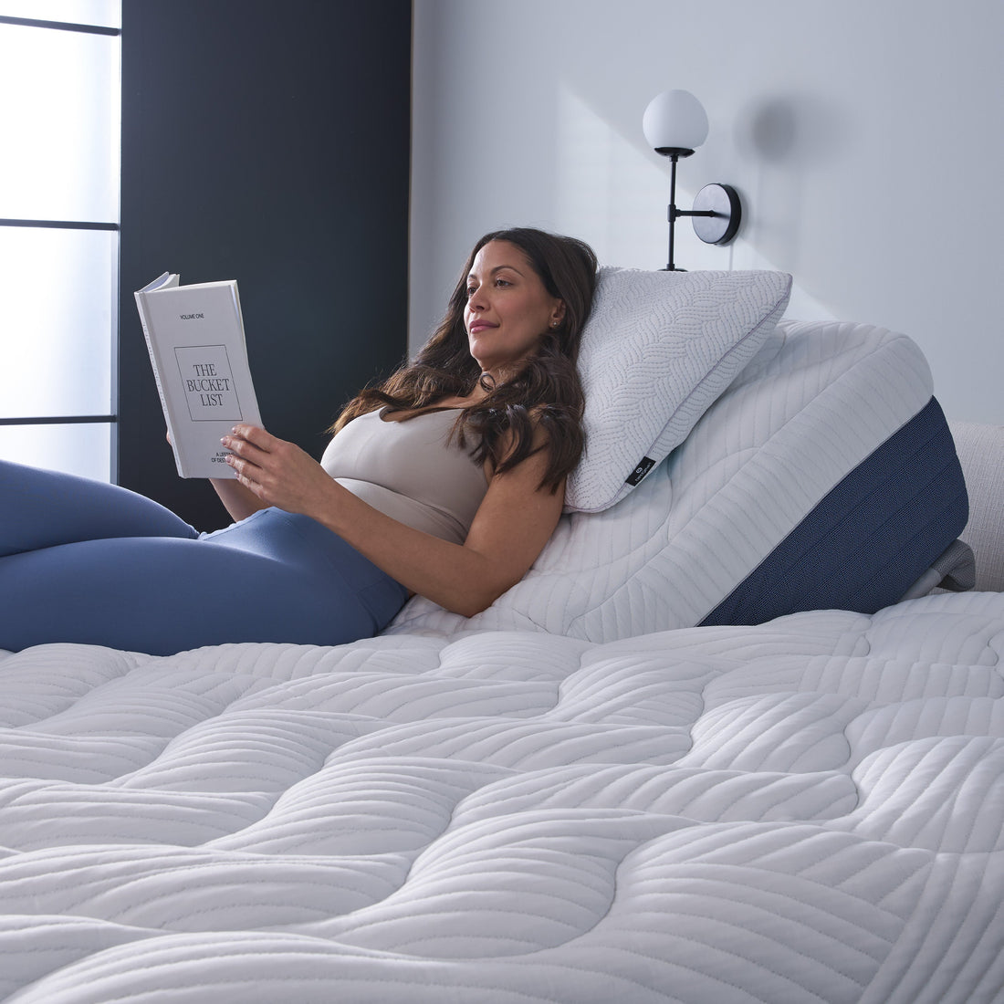 A woman reading on a split head pillowtop mattress. 