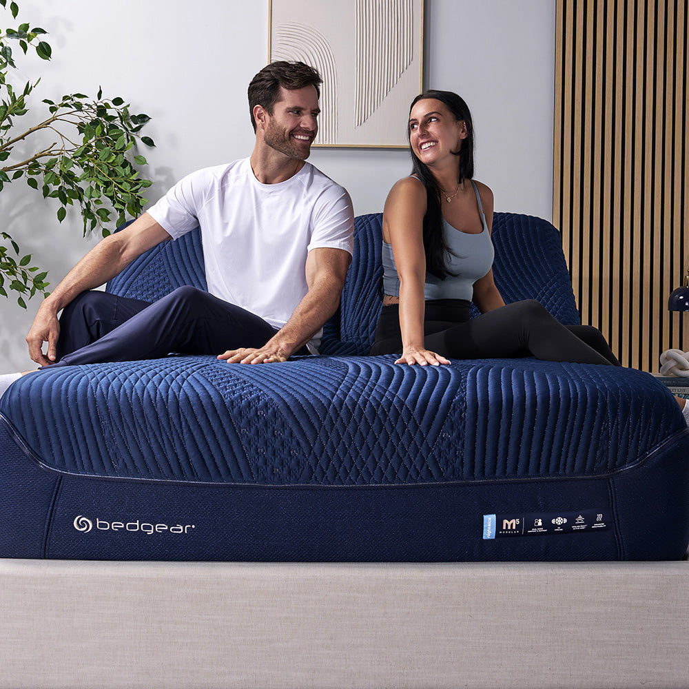 A happy couple resting on a split head king mattress. 