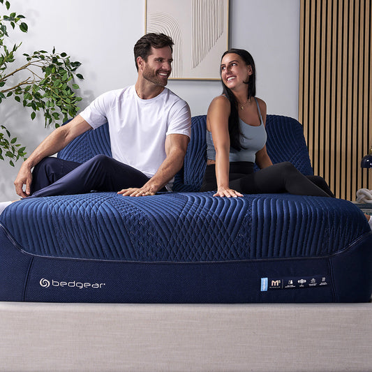 A happy couple resting on a split head king mattress. 
