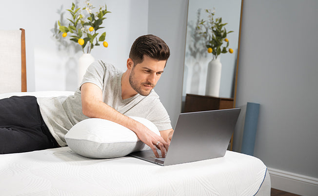 A man leaning over a pillow and learning about how sleep position is shaping your body. 
