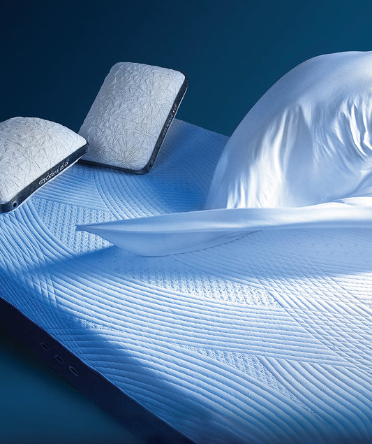 A mattress topper, sheets, and pillows on a bed.