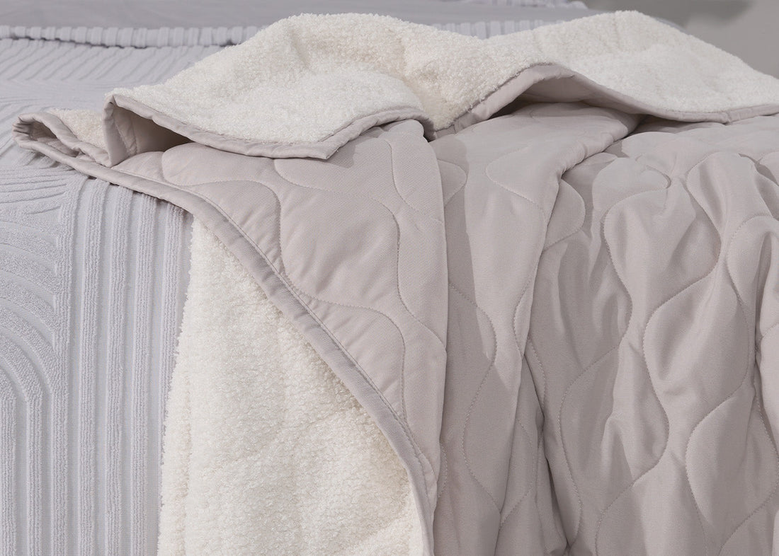 A sherpa blanket on the edge of a bed. 