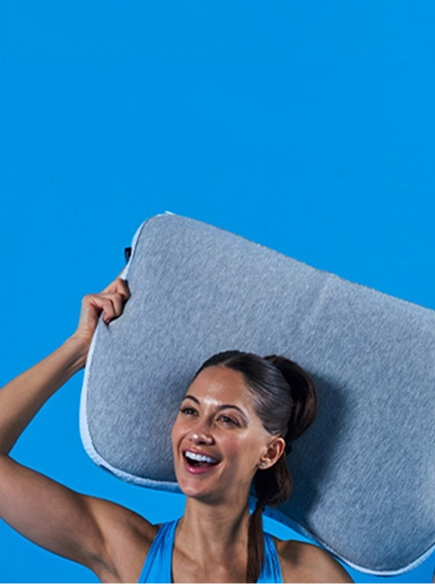 A happy woman smiling with a pillow that helps her sleep apnea.