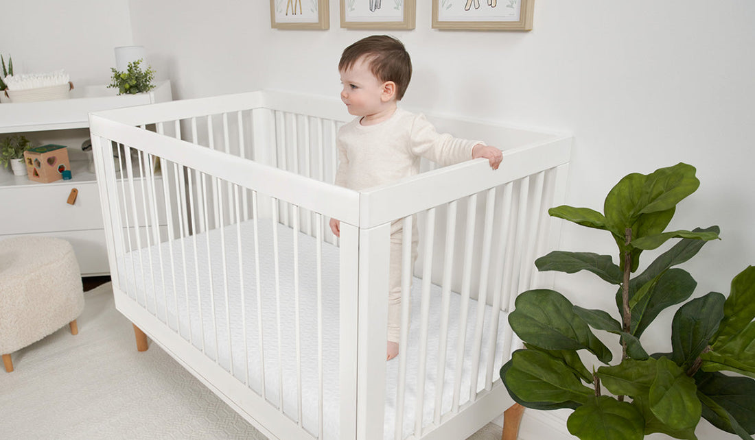 A baby standing in a crib with the appropriate crib mattress size. 