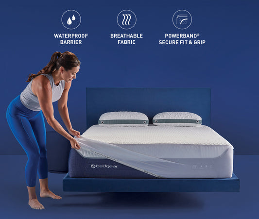 A woman putting a mattress protector on a bed.