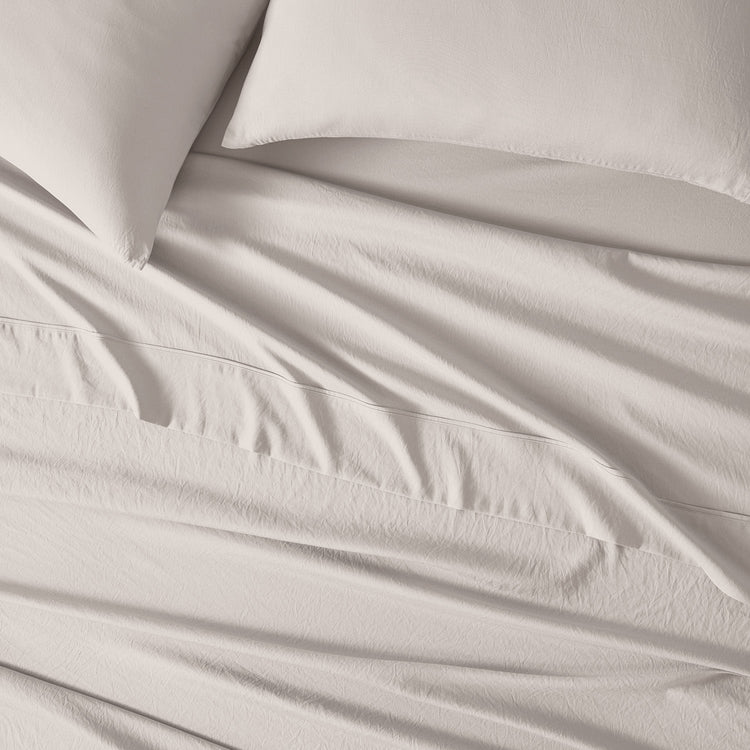 An image of essential sheets on a mattress with two pillows. "taupe"