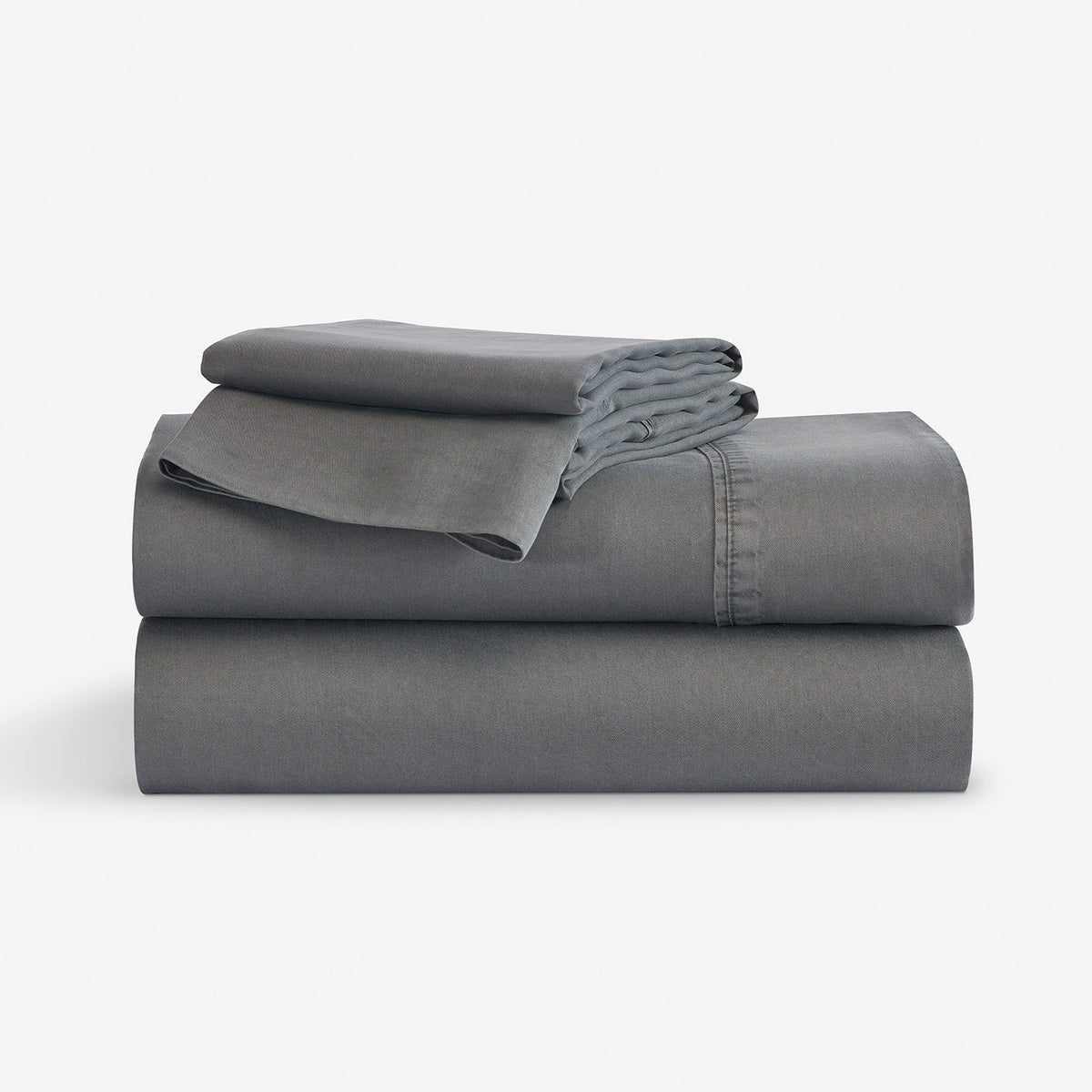 A stack of folded gray bedding, including a folded sheet or duvet and a matching folded pillowcase, photographed on a clean white studio background.