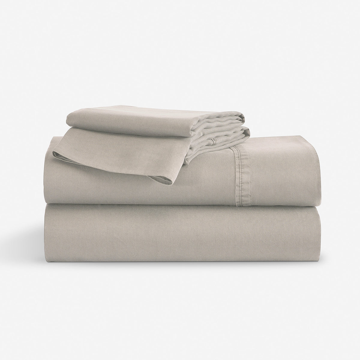 A stack of a folded bedding sheet set, in a light taupe-beige color, photographed against a seamless white studio background.