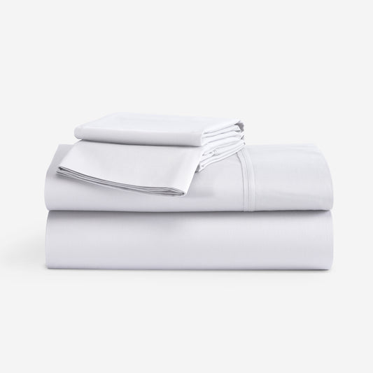 A stack of folded white bedding sheets, including a sheet and a folded pillowcase, on a clean white background. "Bright White"