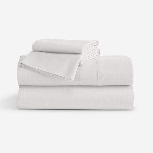 A stack of folded white bedding, including sheets and pillow cases, photographed on a clean white studio background. "Ivory"