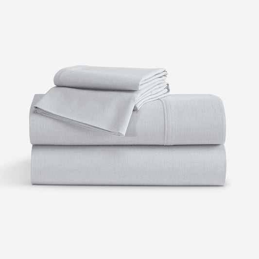 A stack of folded light gray bedding, including a folded sheet and two folded pillowcases, photographed on a clean white studio background. "Light Grey"