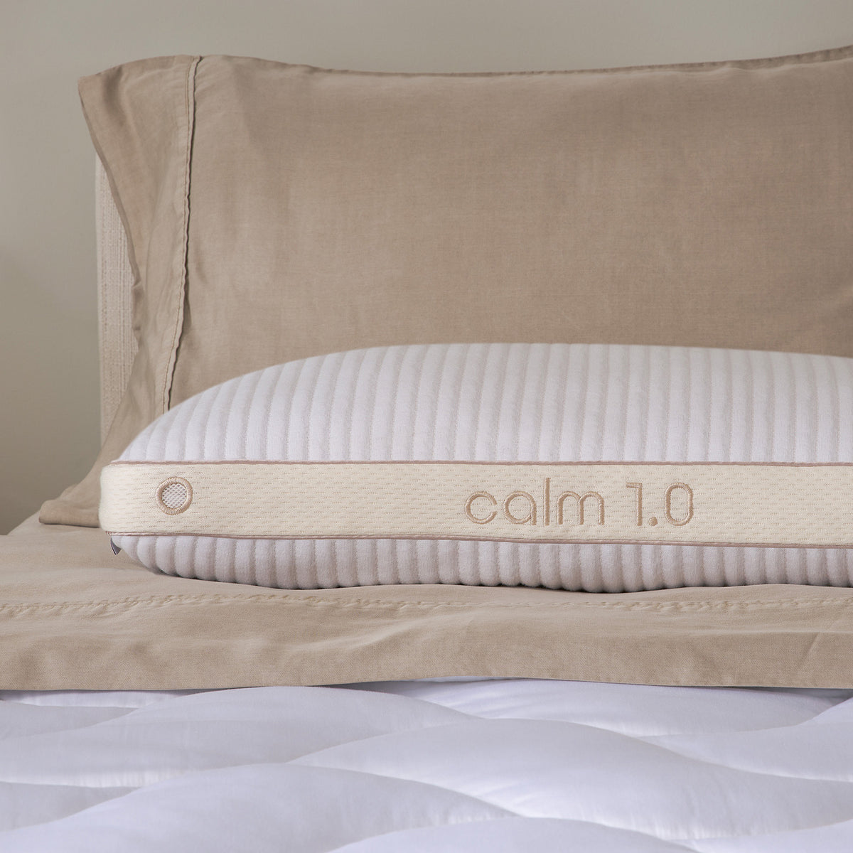 A close-up of a calm 1.0 pillow resting on a quilted mattress.