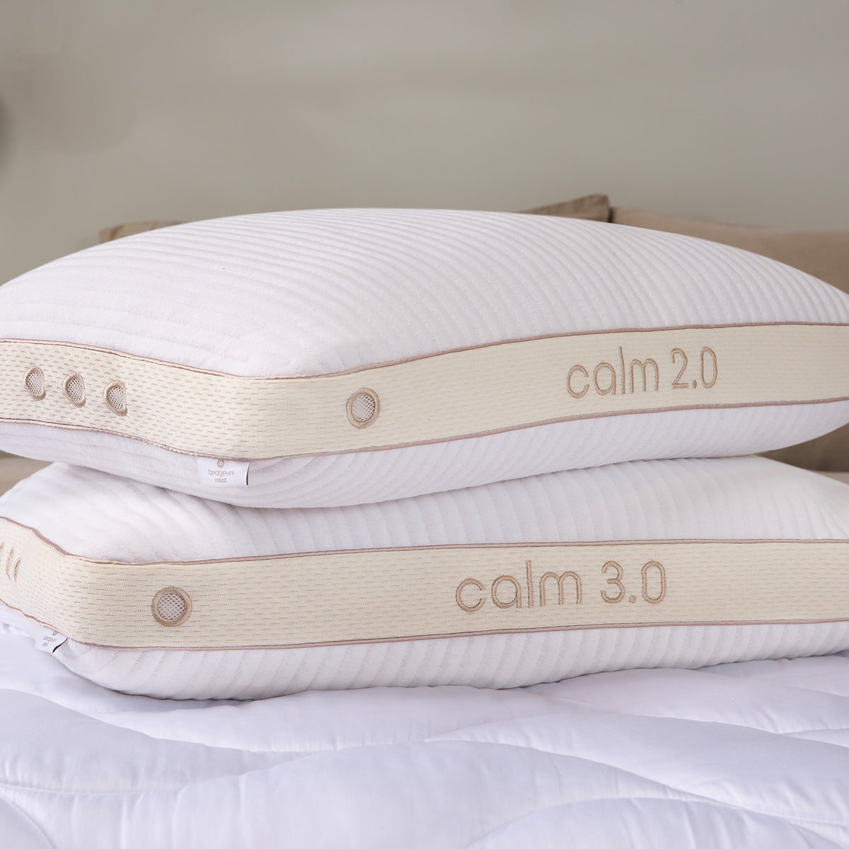 Two stacked calm pillows on a white quilted bedspread.