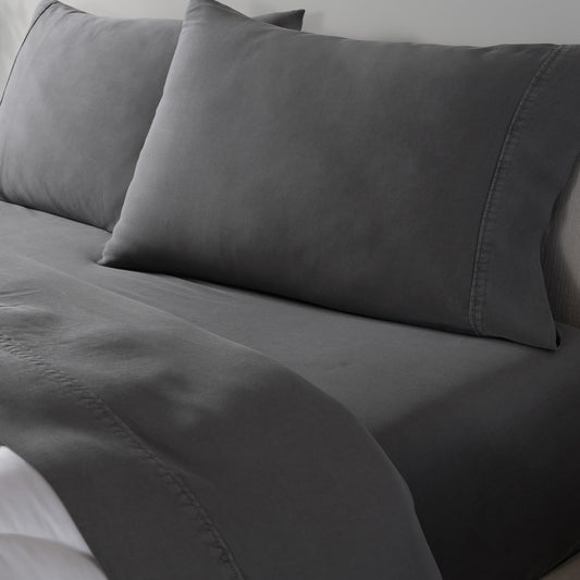 Dark gray bedding set including a fitted sheet and two matching pillowcases on a bed. 