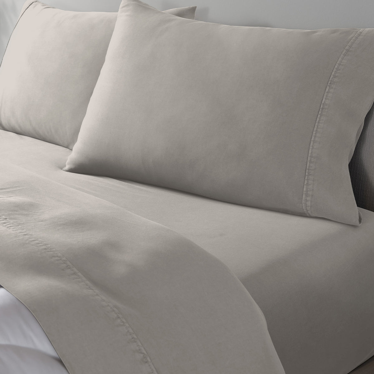 Light beige bed sheet set with matching pillowcases on a bed, shown in a close-up view.