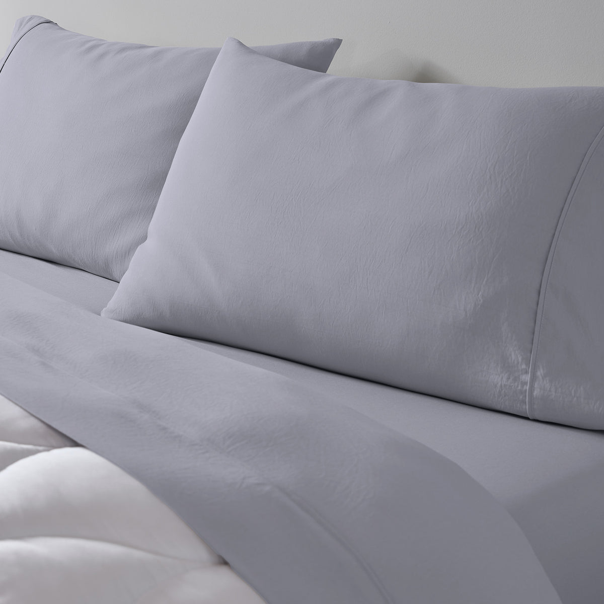 A light grey essential sheet set on a made bed.