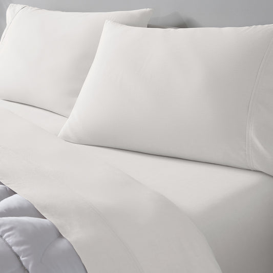 Ivory bedding set including a flat sheet, pillowcase, and two pillows on a bed. 