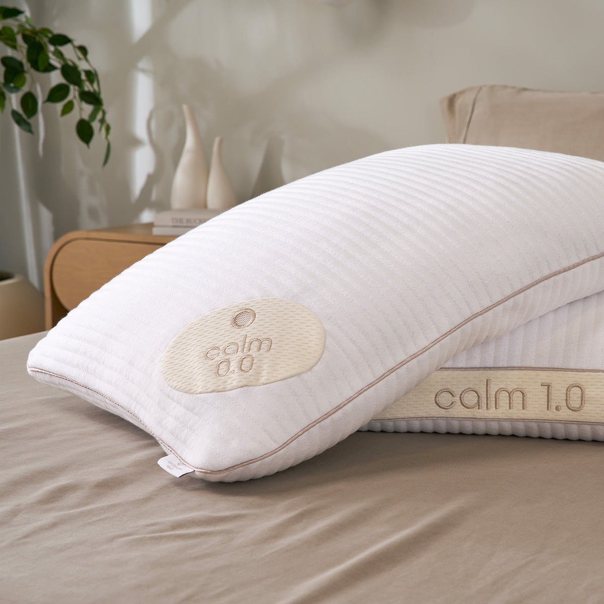 Two Calm Performance Pillows resting on a beige bed.