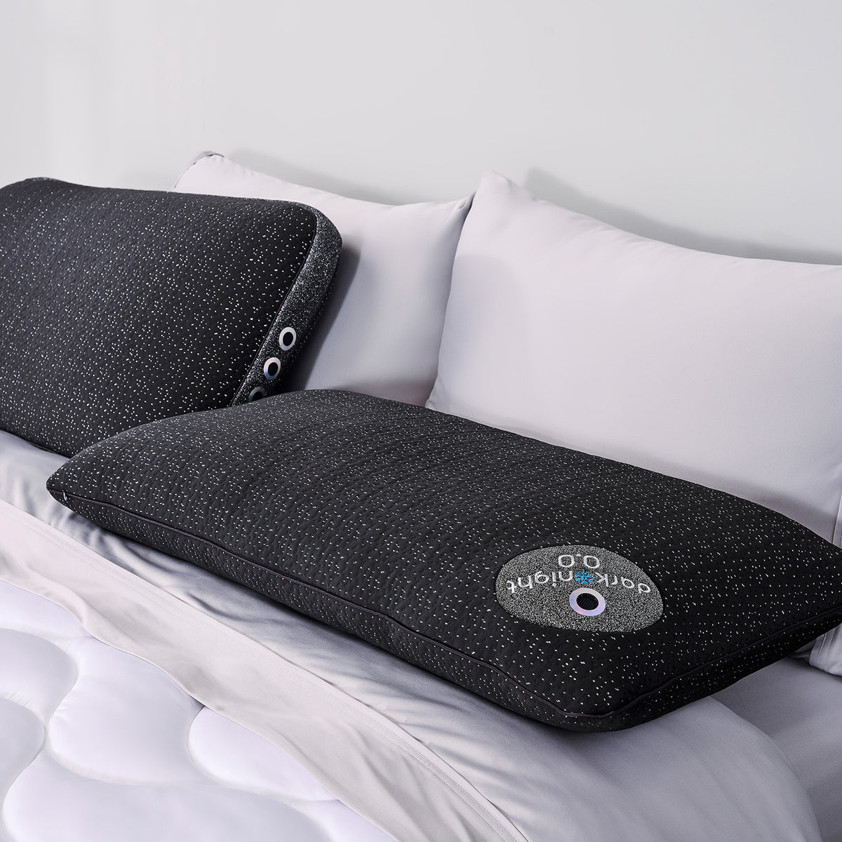 Two dark night pillows on a bed with white bedding.