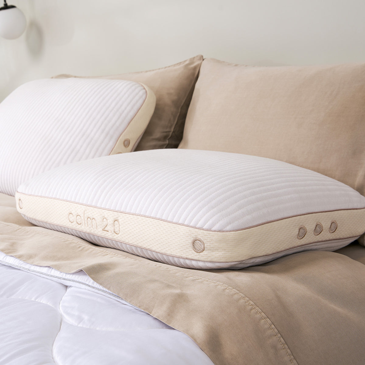 Two calm pillows with beige trim and buttons, resting on a  bed.