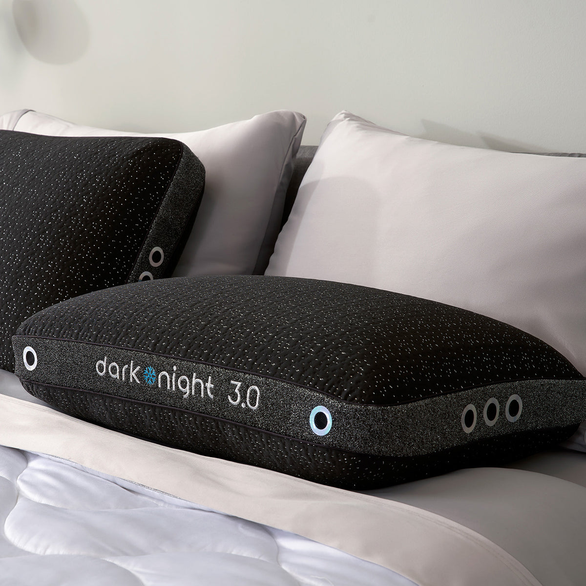 A set of dark night pillows resting on a white comforter in a bedroom setting.