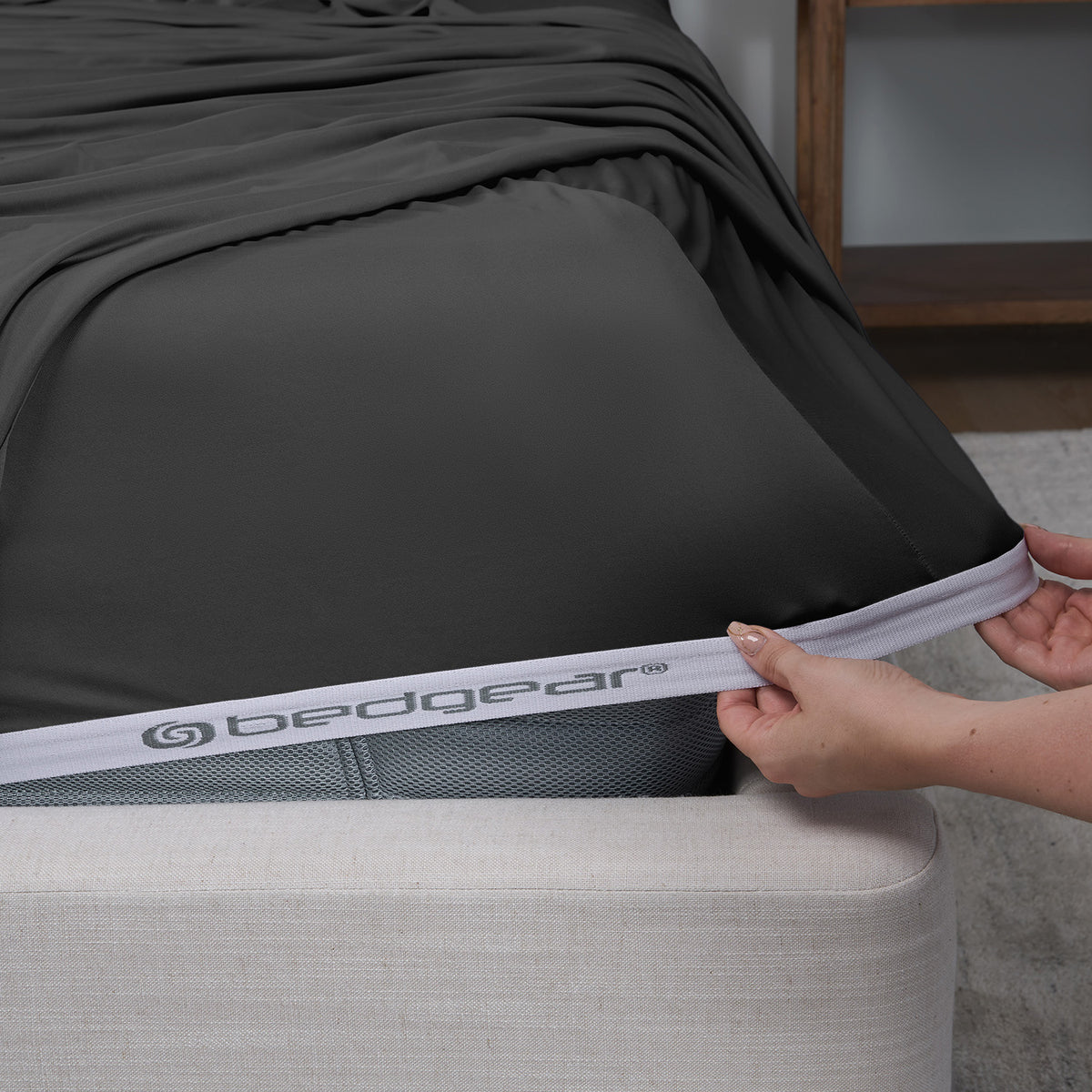 A woman pulling BEDGEAR fitted sheets over a mattress.