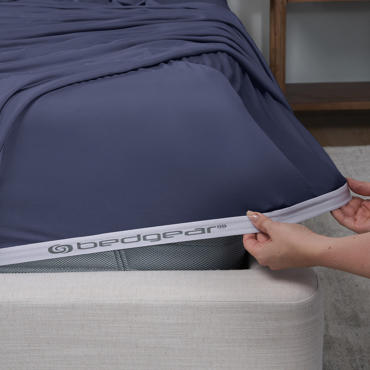 A woman pulling blue sheets over a mattress.