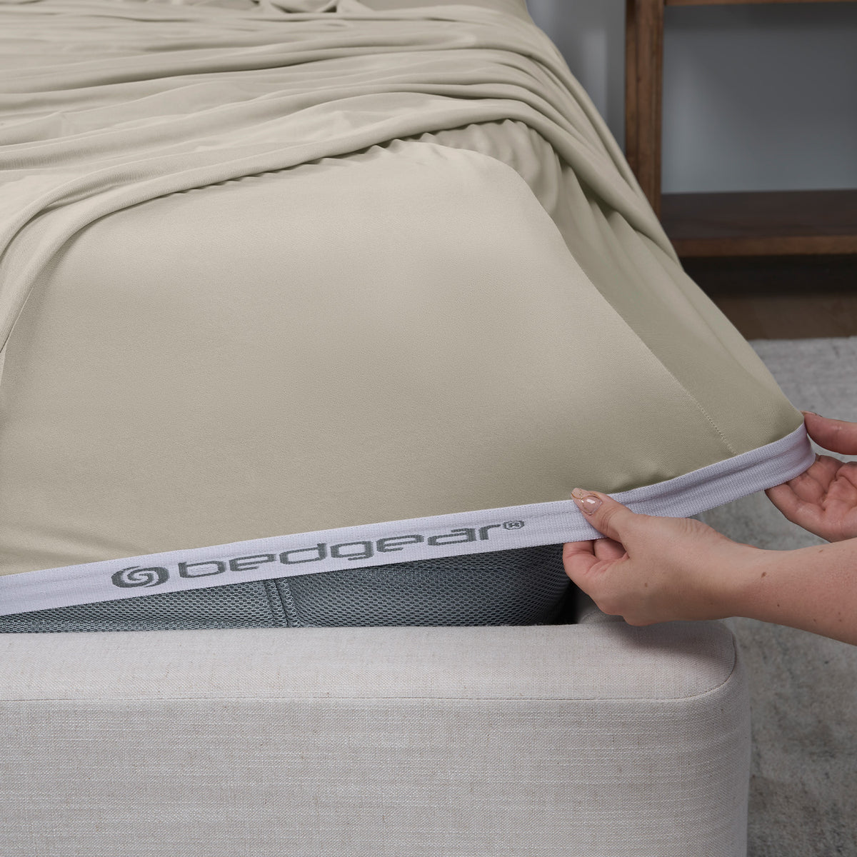 A woman pulling a fitted sheet over a mattress.