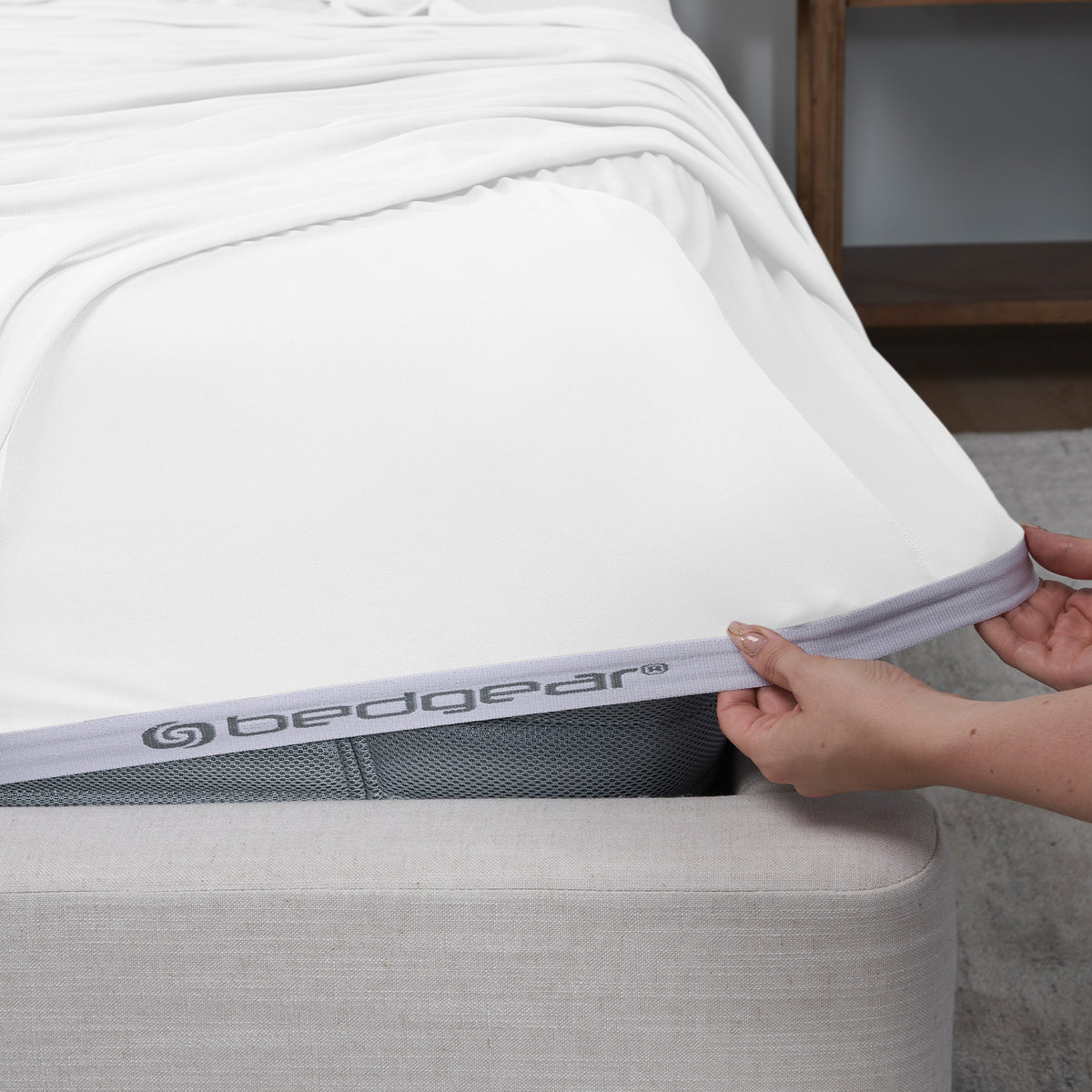 A woman pulling a white DriTec fitted sheet over a mattress.