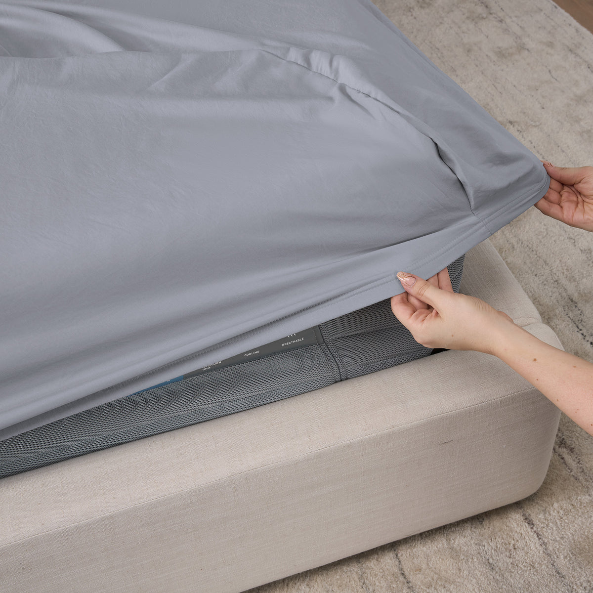 A woman making a bed with essential BEDGEAR sheets.