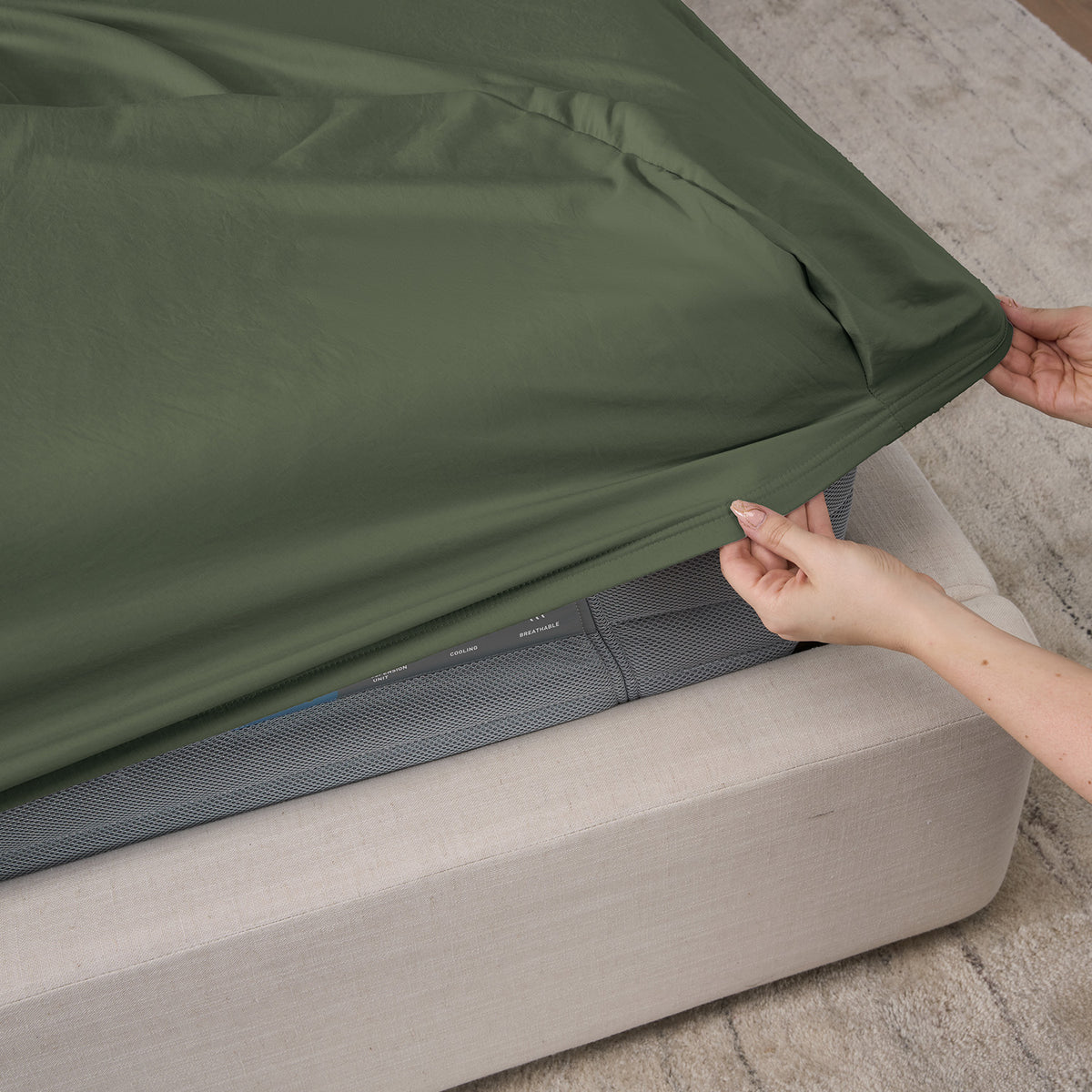 A woman putting moss sheets on a bed.