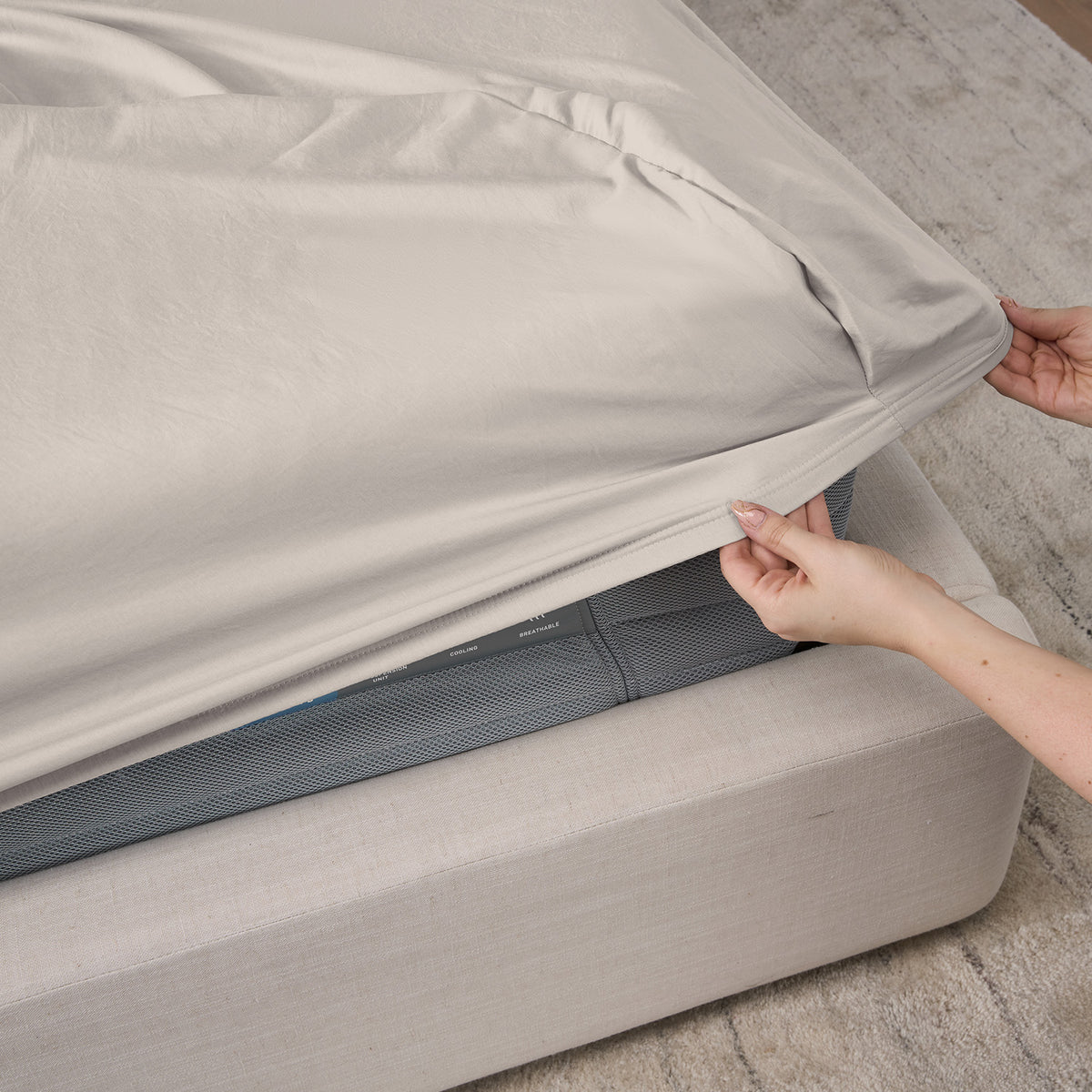A woman making a bed with essential sheets.