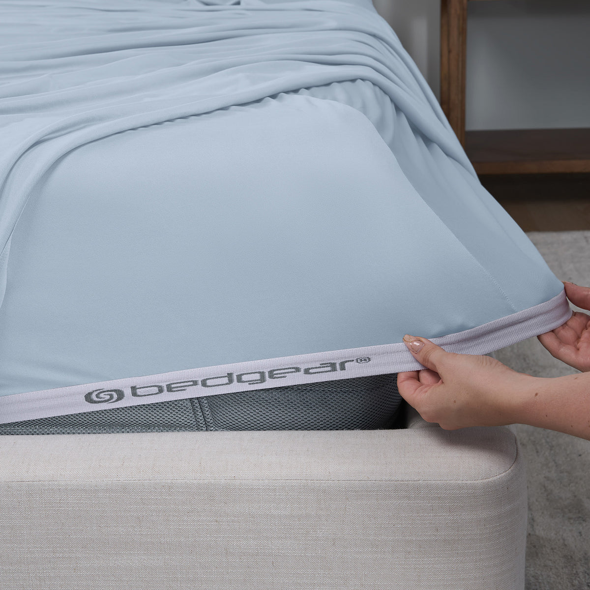 A woman pulling blue sheets over a mattress.