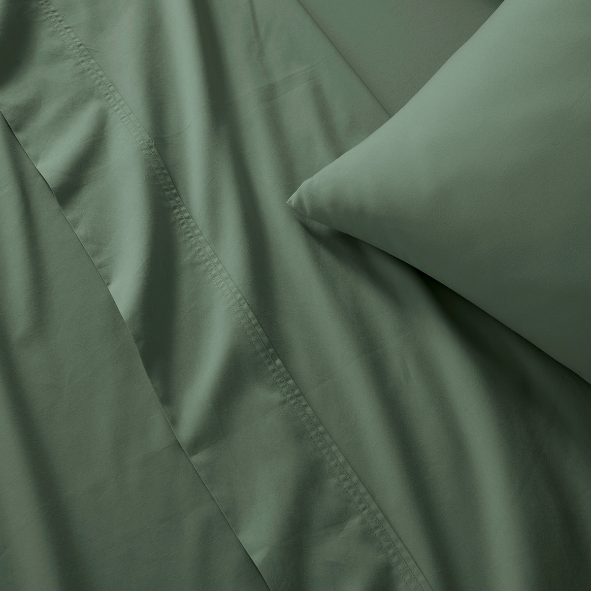 Close-up of moss green bedding with a pillowcase and visible stitched edge detail.