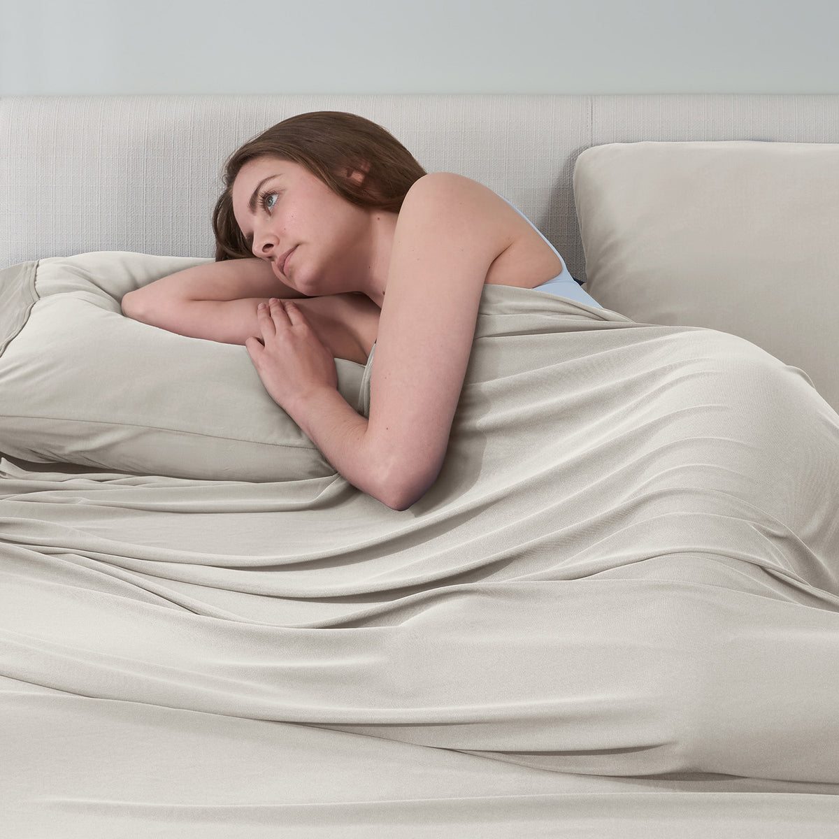 A woman lying in bed with tan DriTec sheets.
