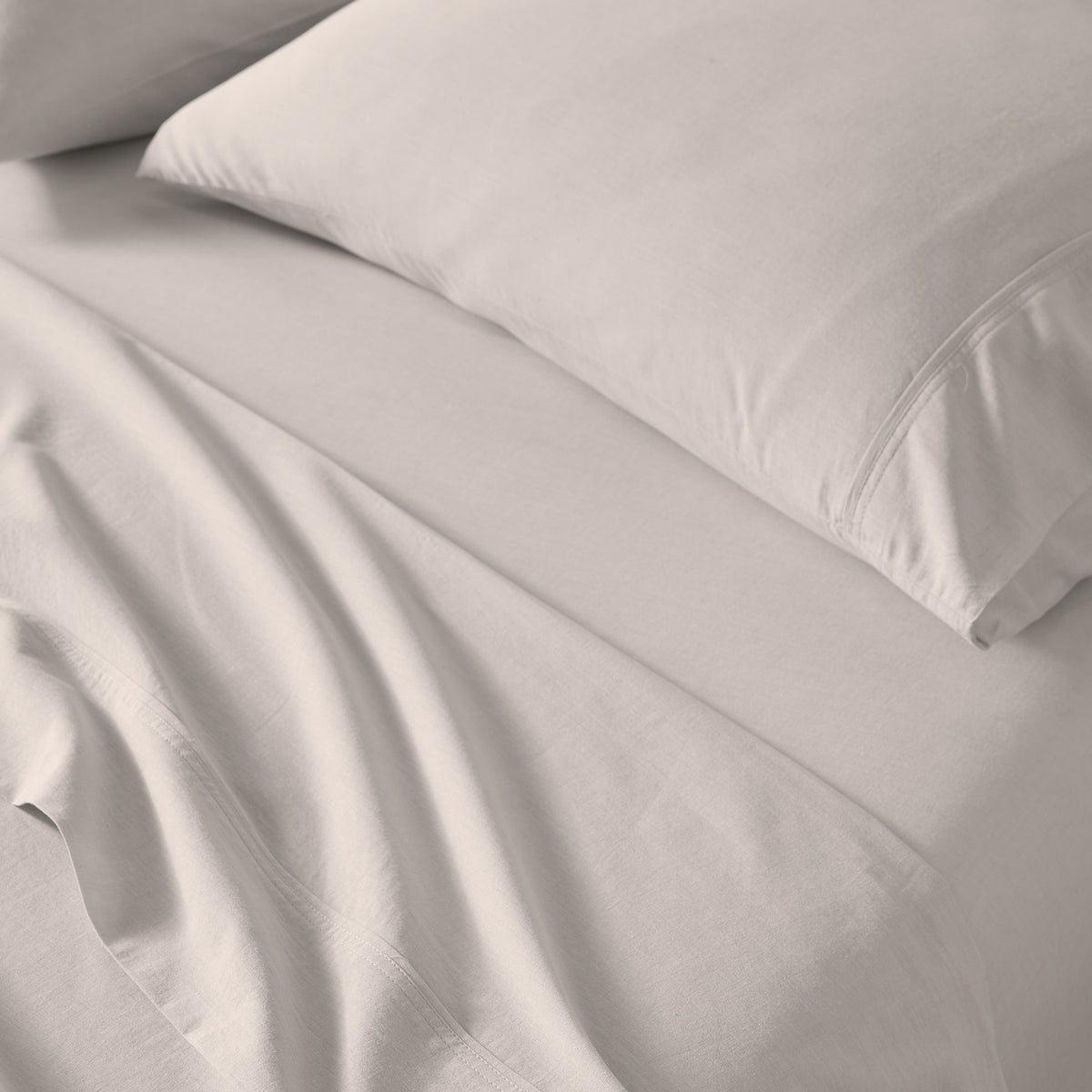 Taupe bed sheets and a matching pillowcase on a bed, shown in a clean close-up view with soft folds and no visible branding.