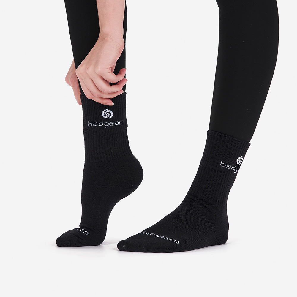 A close-up shot of a woman putting on BEDGEAR crew socks. 