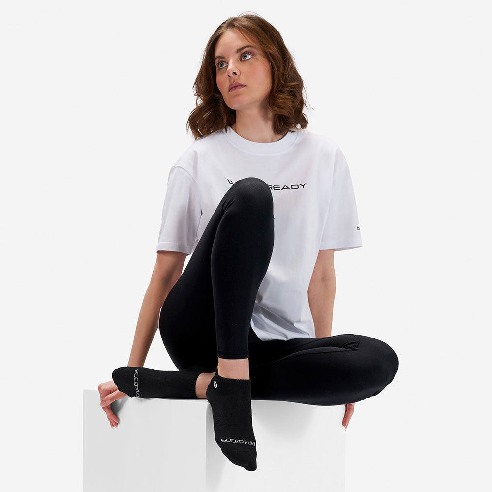 A woman wearing a Wake Ready shirt and Sleep Fuel socks. 