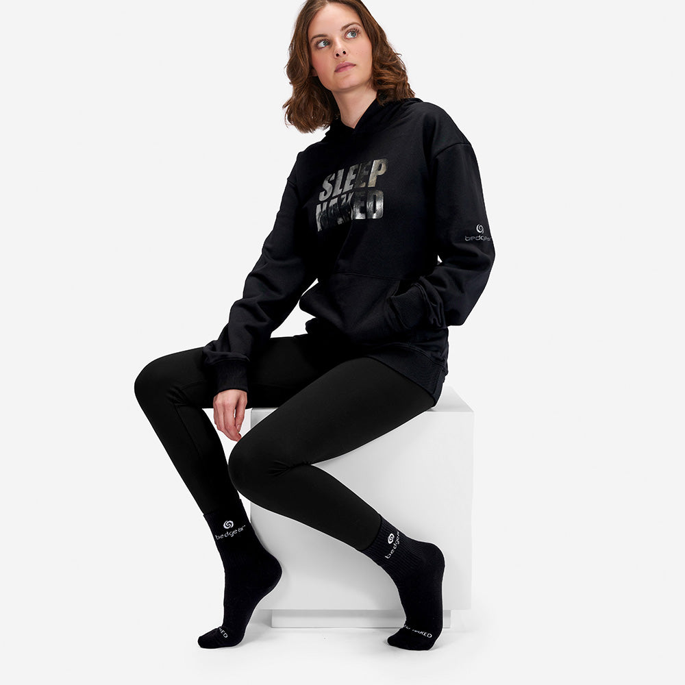 A woman wearing a Sleep Naked hoodie and Sleep Naked socks. 