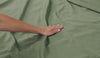 A woman moving her hand along green BEDGEAR cotton sheets. 