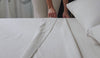 A woman unfolding linen bed sheets. 