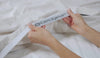 A woman holding BEDGEAR Powerband sheets. 